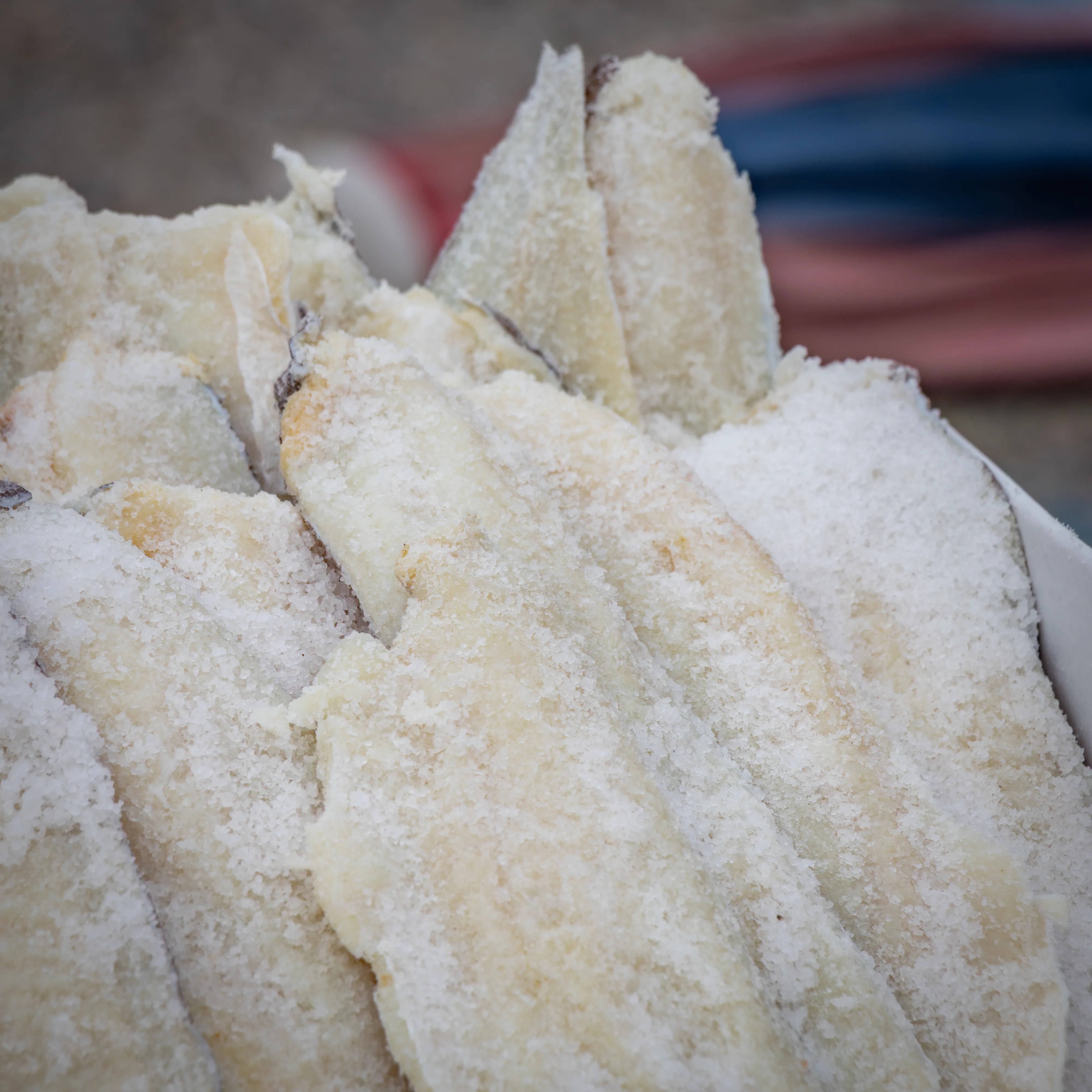 Fish coated in coarse salt piled together in a container.