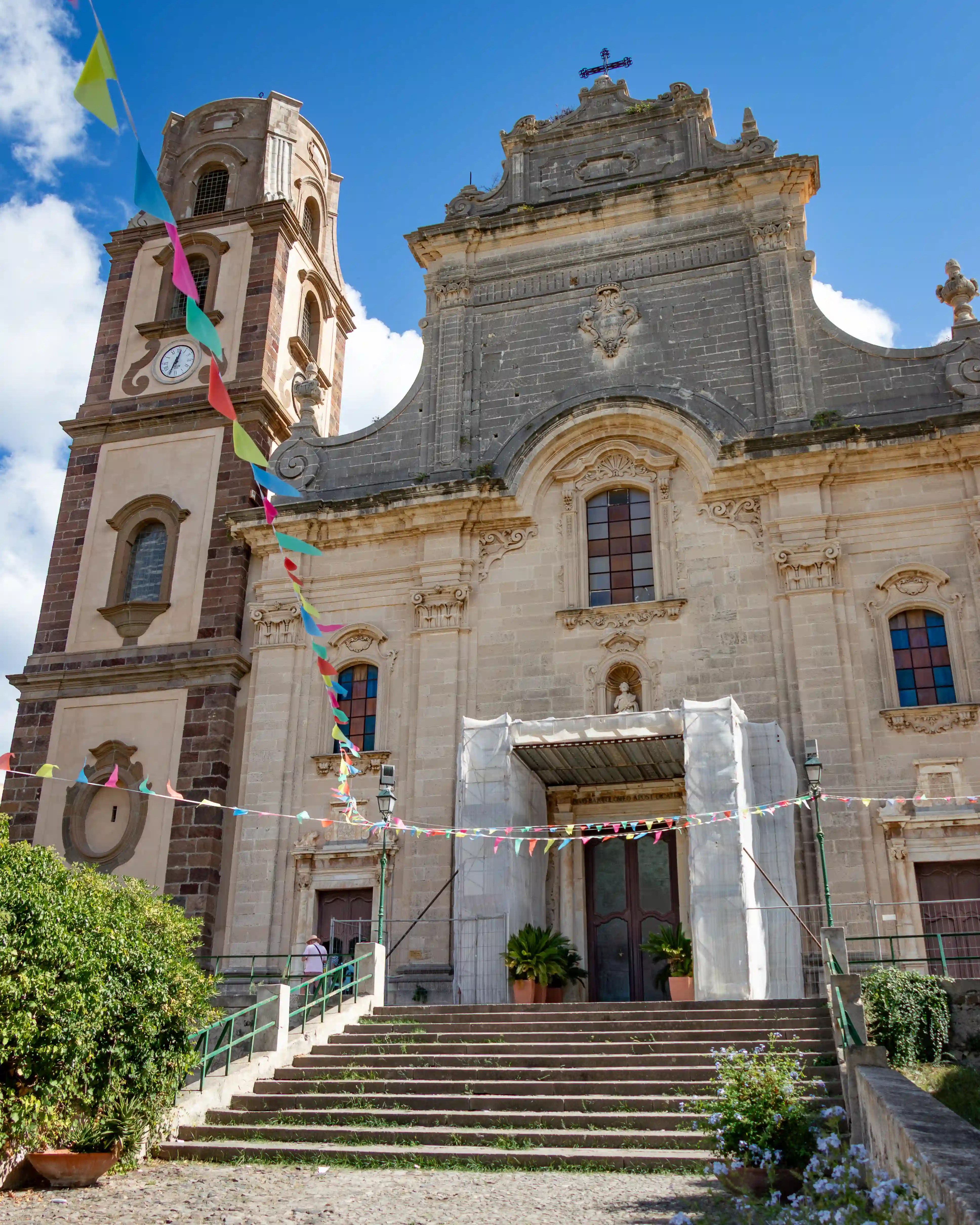 Large stone church facade with steps leading up to the entrance and a bell tower beside it.