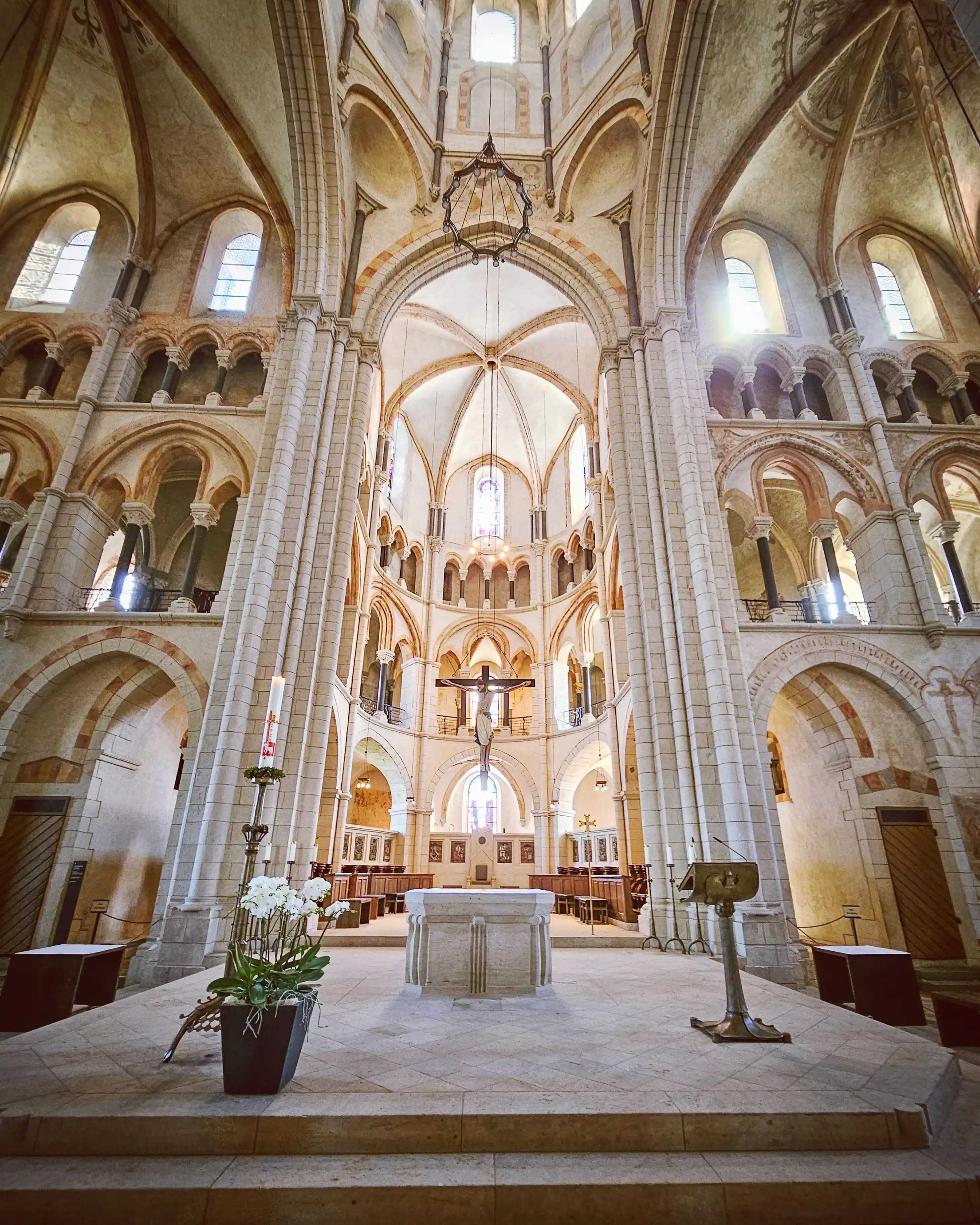 A cathedral altar stands beneath tall columns, rounded arches, vaulted ceilings, and a crucifix.