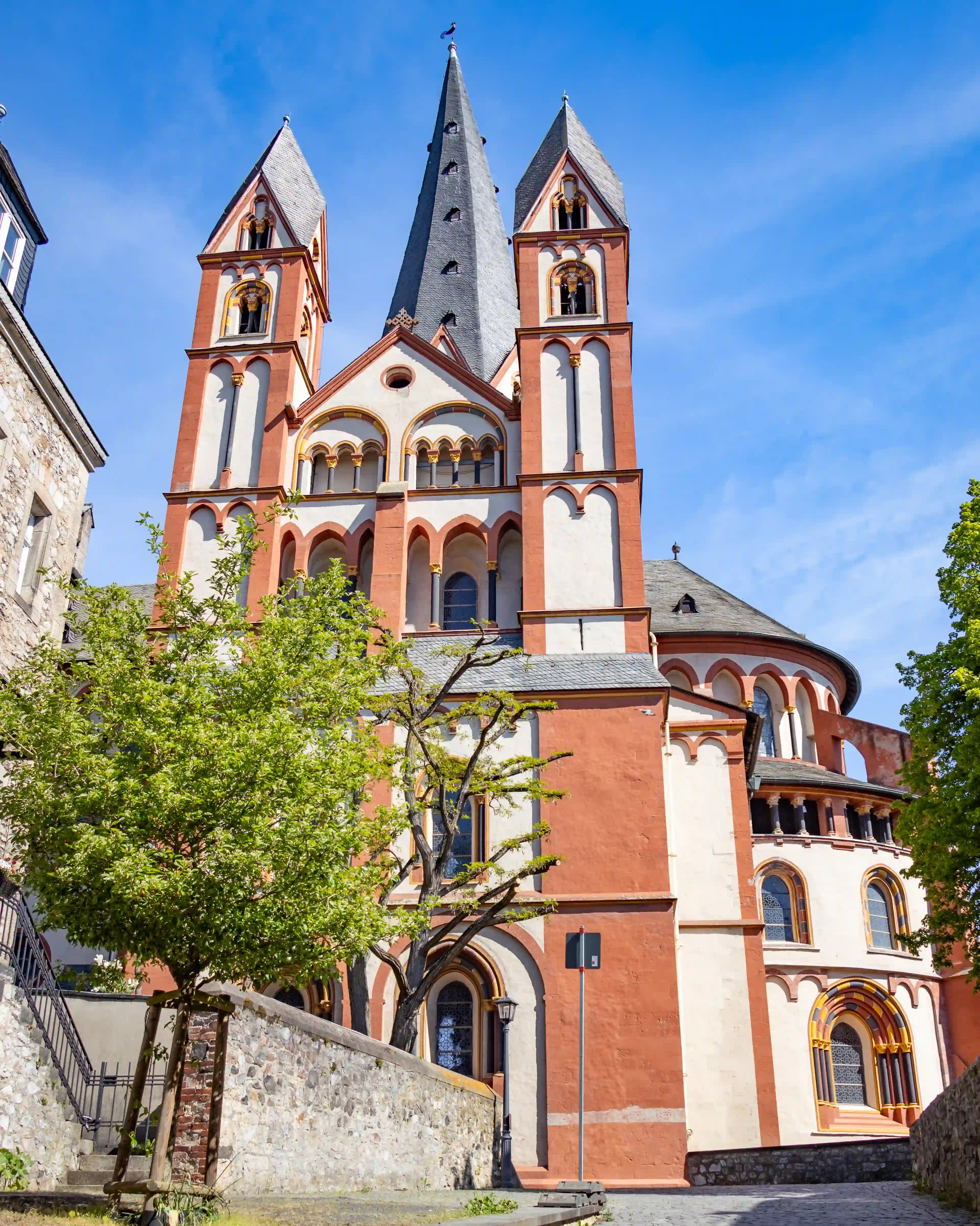 Limburger Dom with red-and-white towers rising above stone walls and trees in Limburg an der Lahn.