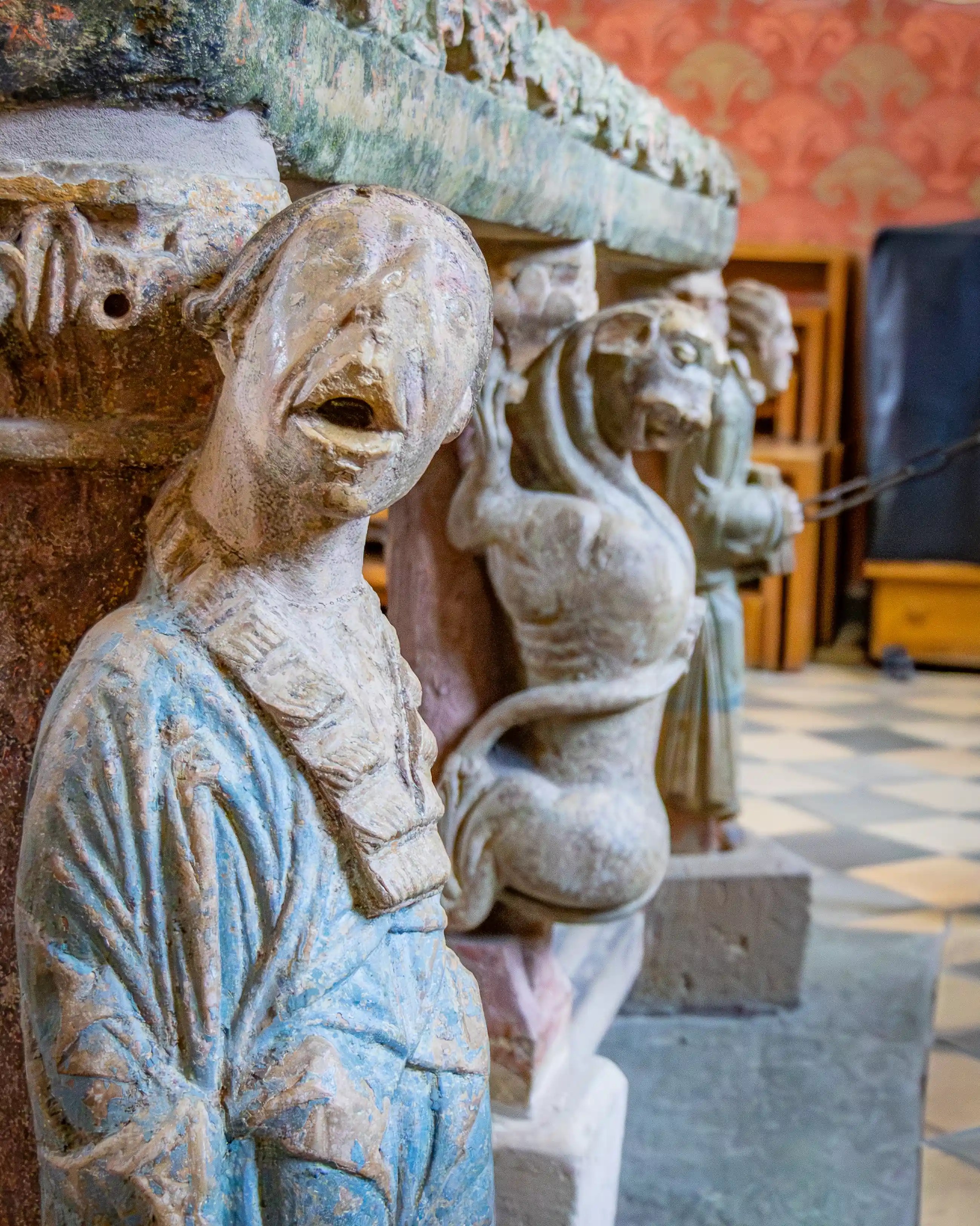 A close-up shows carved figures on a stone tomb inside a church.