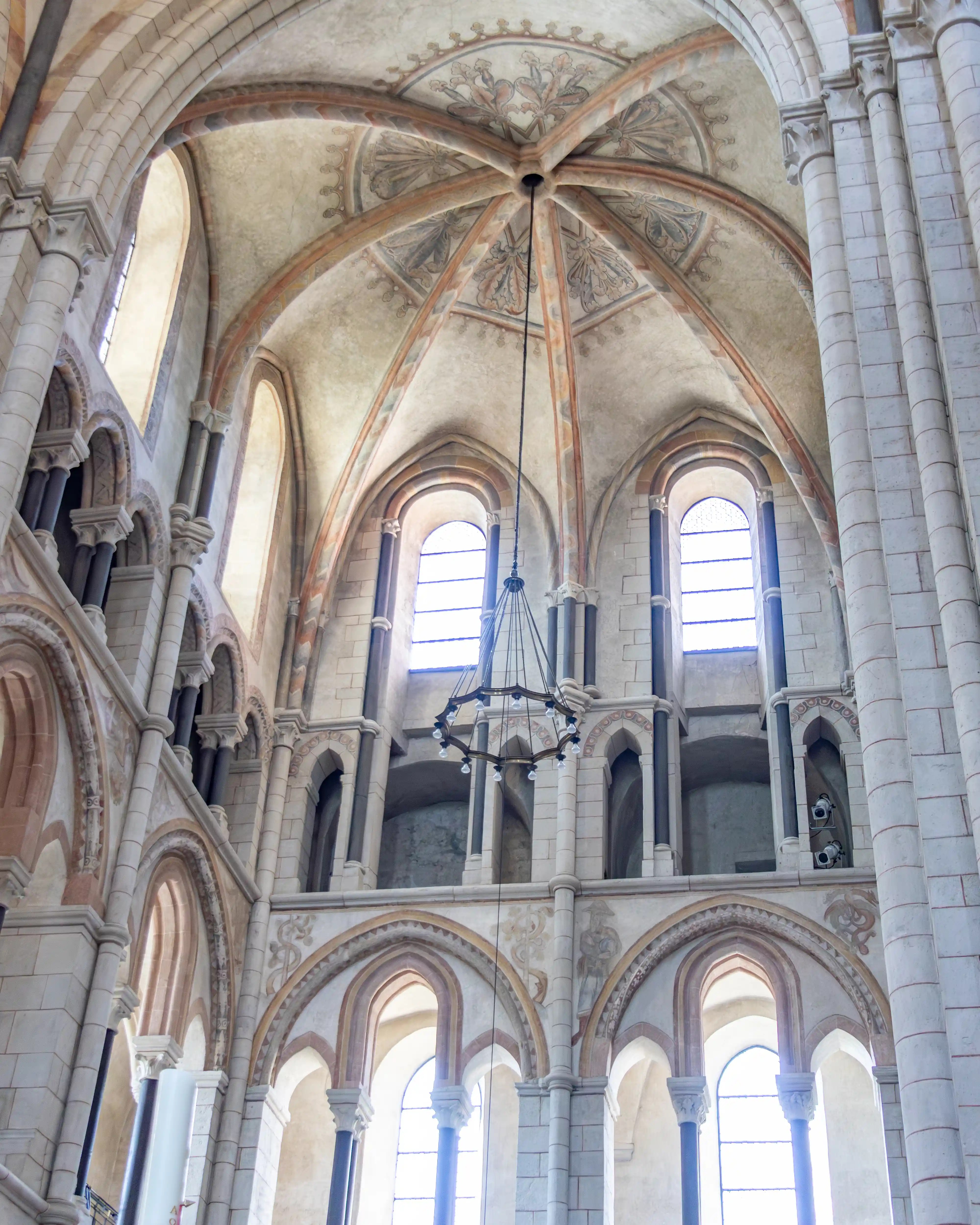 Arched windows and painted vaults rise above columns inside a cathedral.
