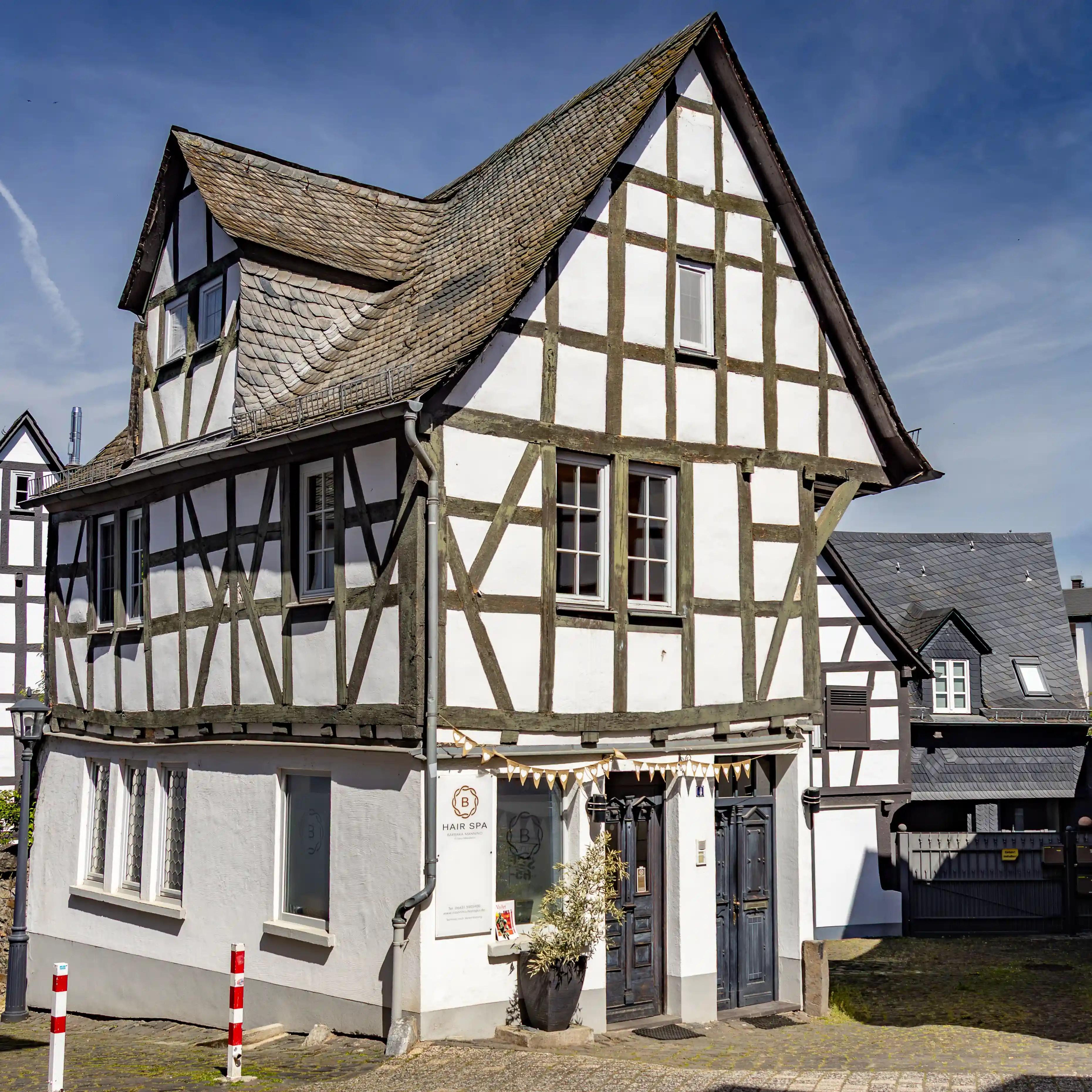 A half-timbered building stands on a cobblestone street under a blue sky.