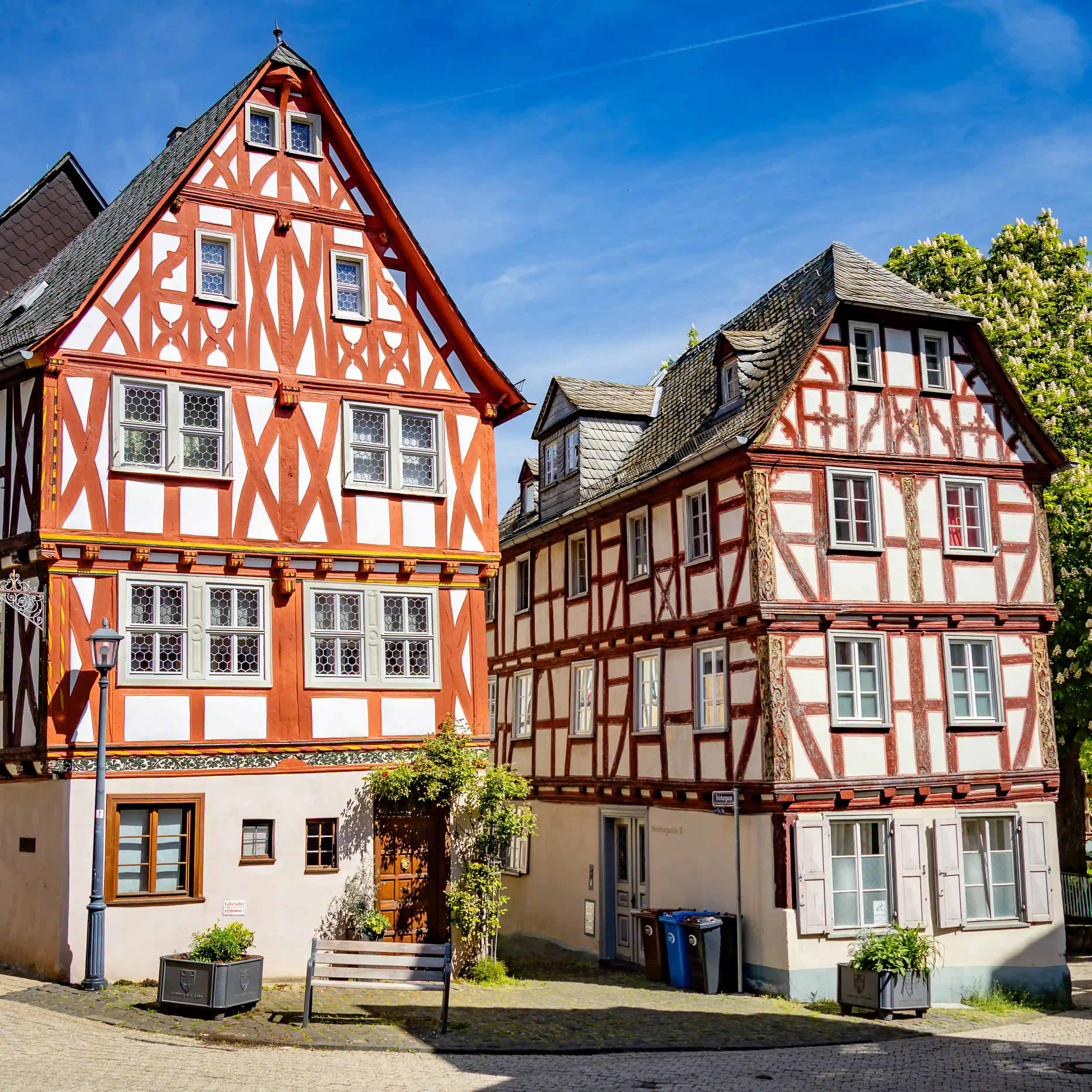 Two red-and-white half-timbered houses stand beside a narrow cobblestone street.
