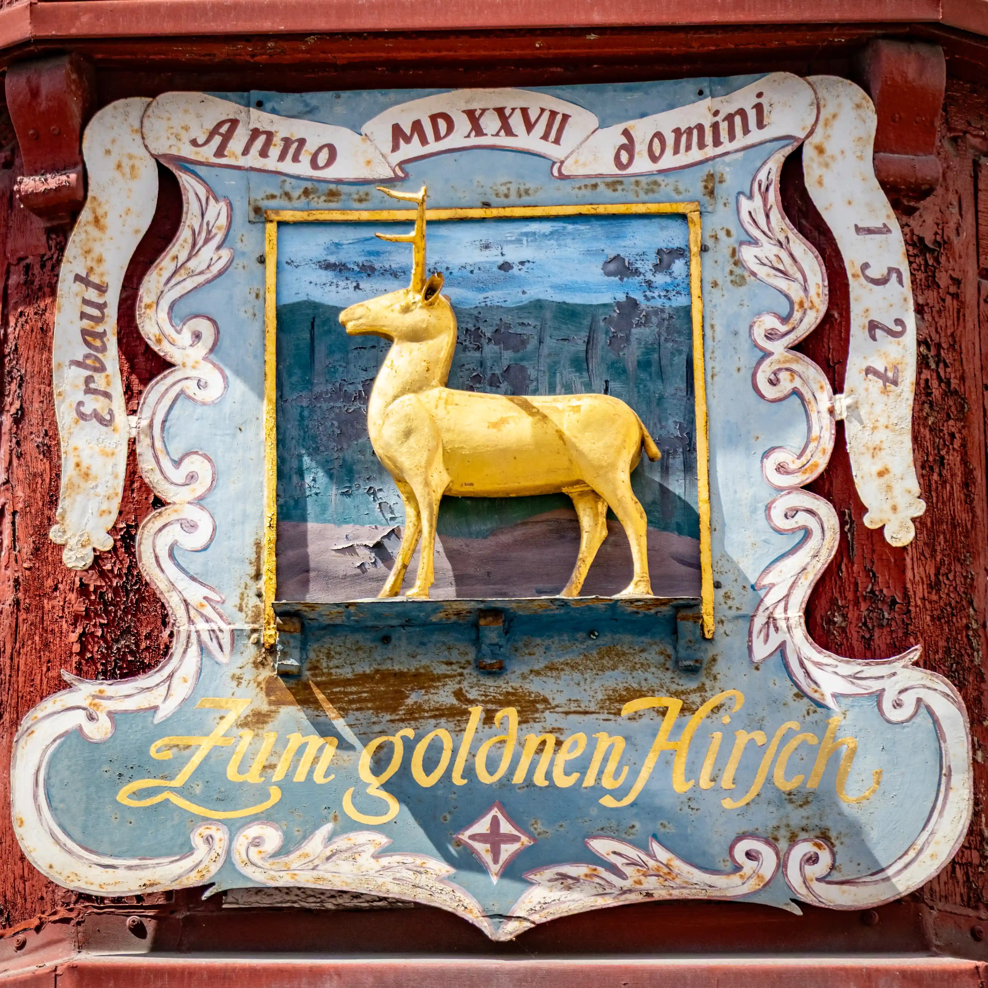 A painted sign shows a golden deer and the words “Zum goldenen Hirsch.”
