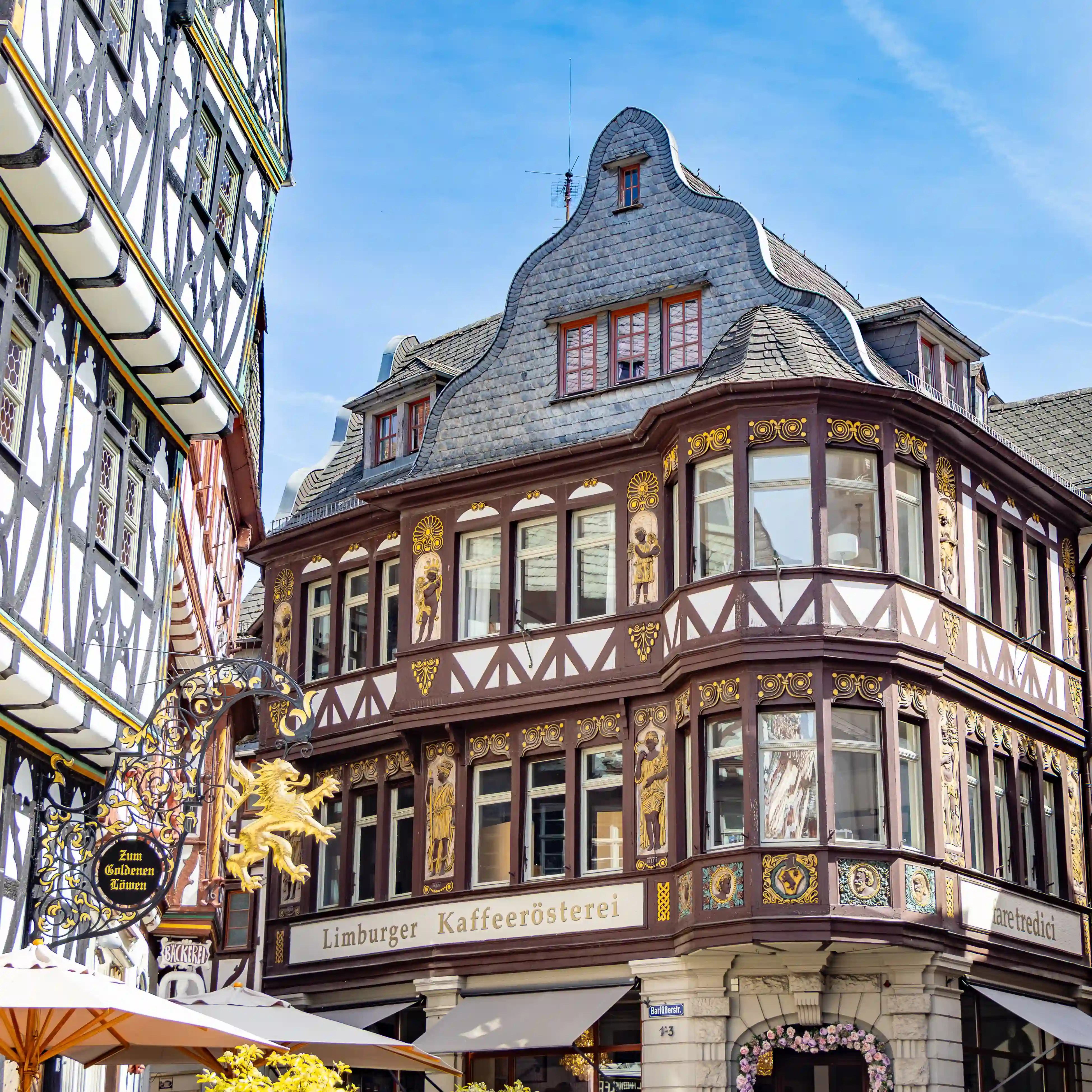 An ornate half-timbered building has gold details and a sign for Limburger Kaffeerösterei.