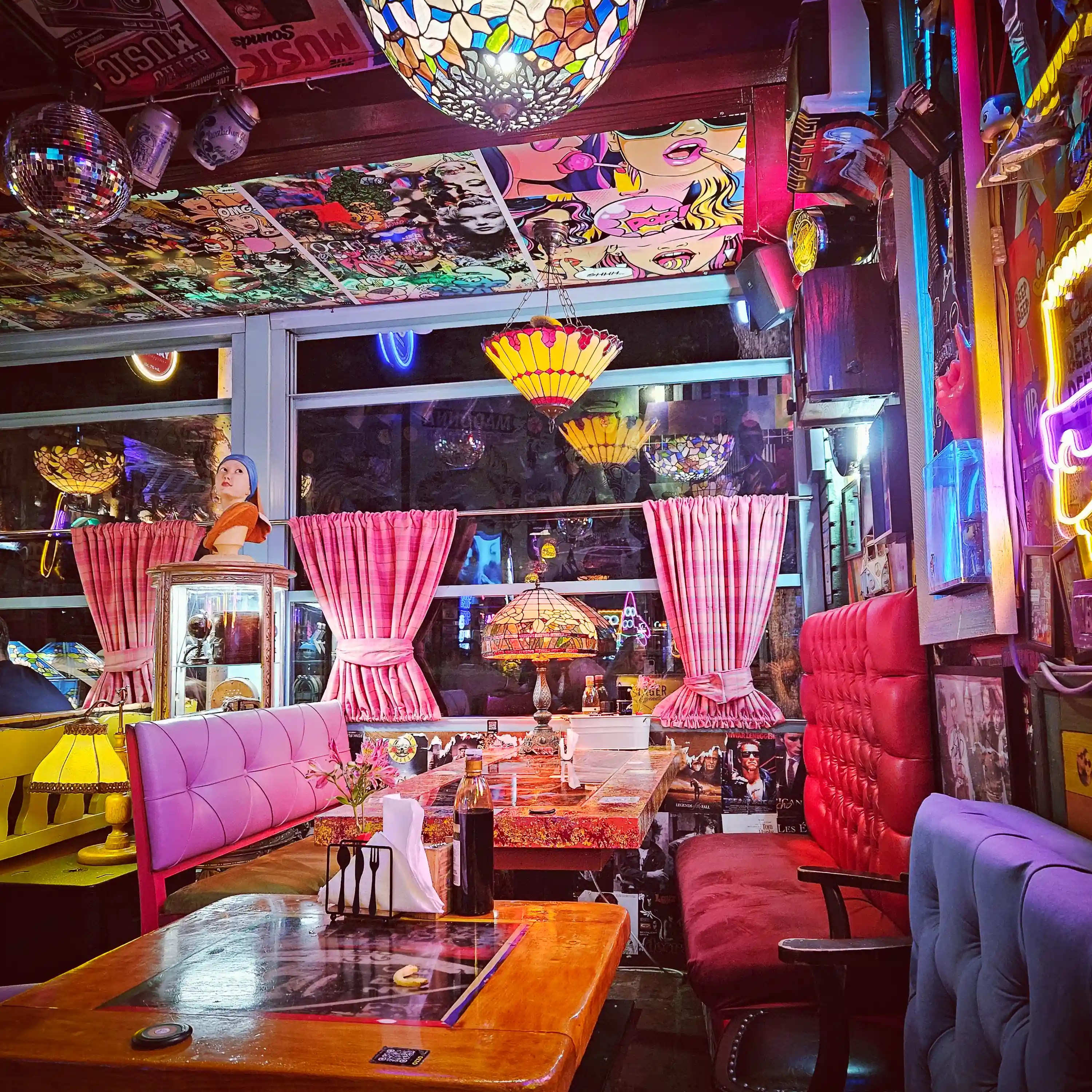 Colorful seating, vintage lamps, and pop culture artwork inside Restorant Tymi in Tirana.