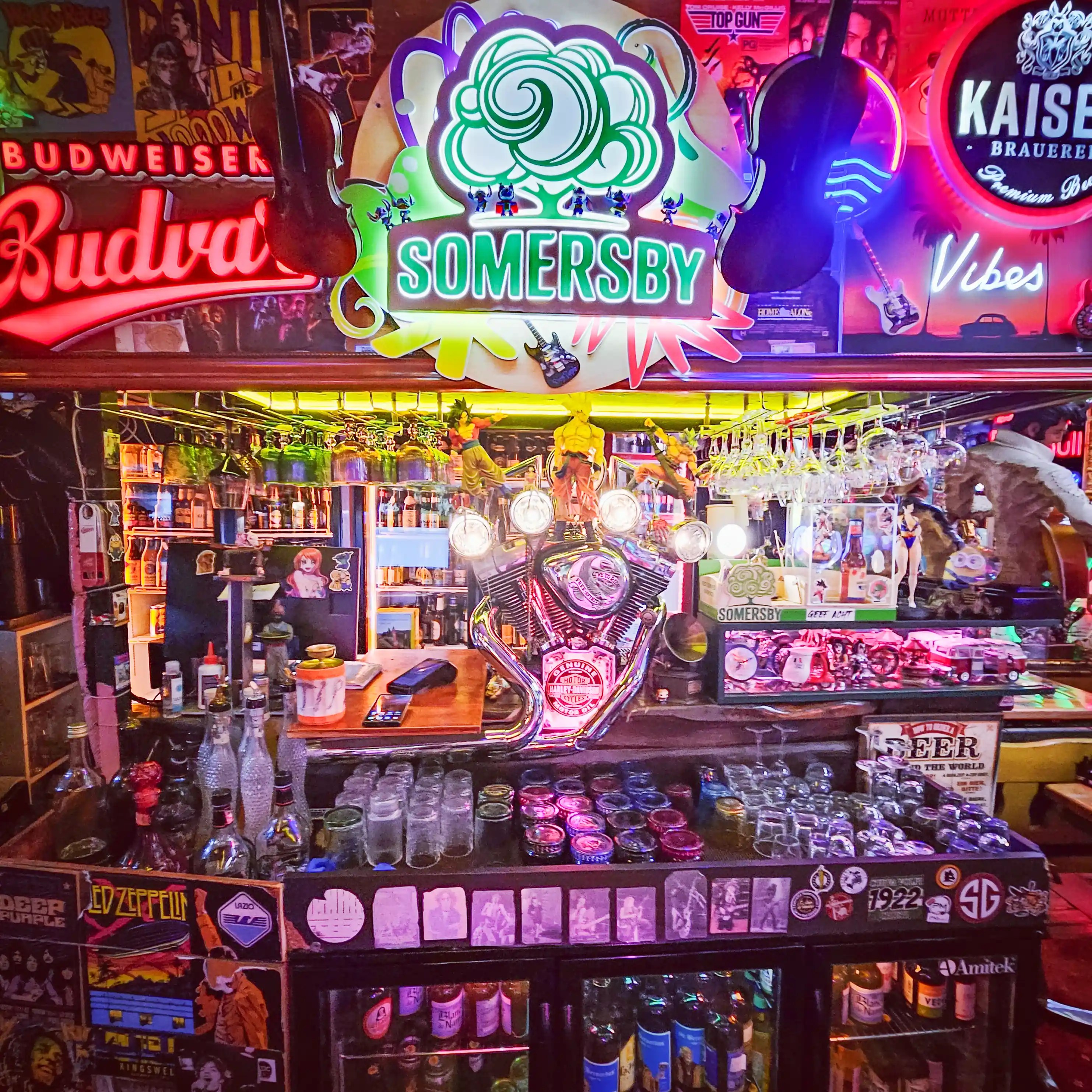 A brightly lit bar filled with neon signs, musical decorations, and memorabilia inside Restorant Tymi in Tirana.