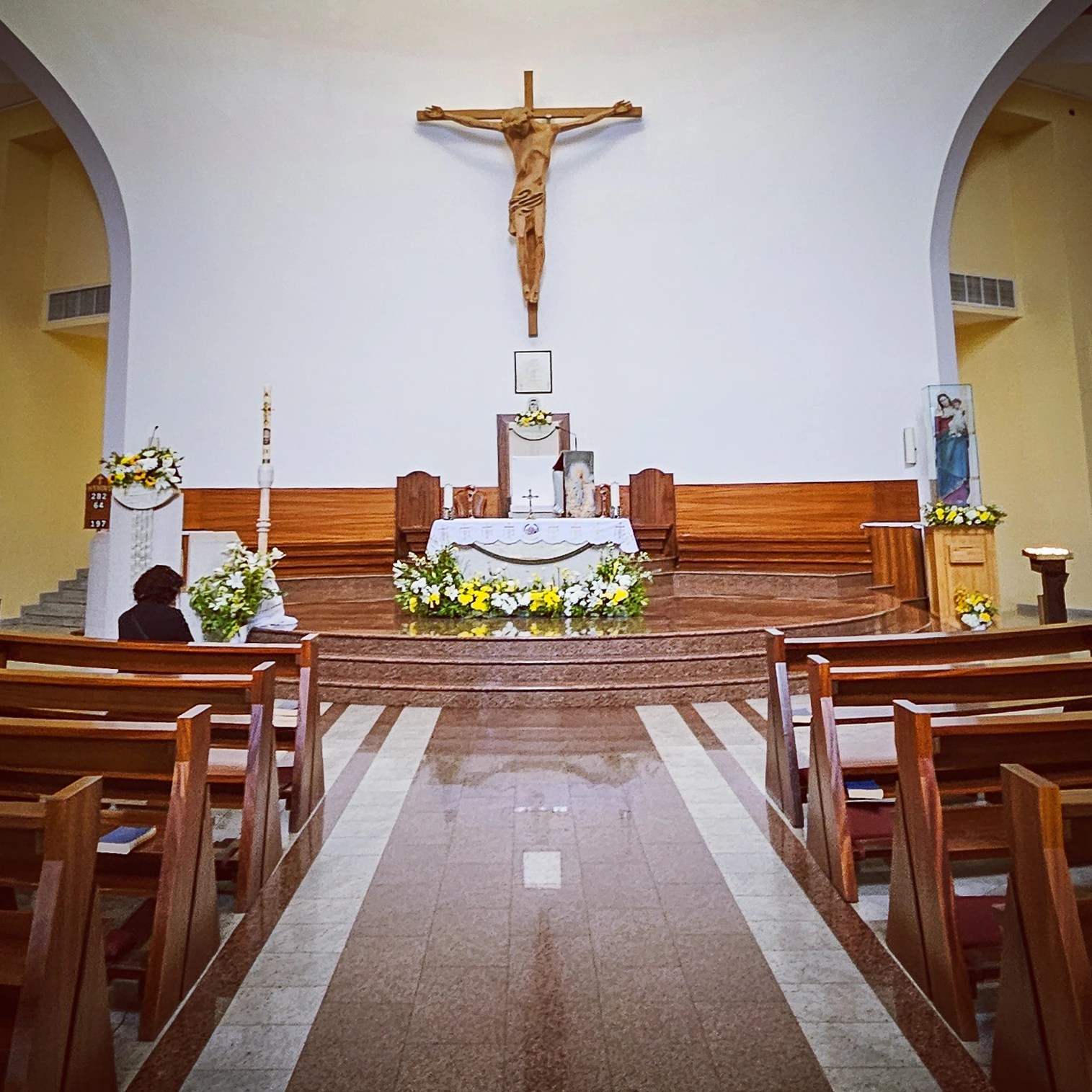 Interior of St. Paul's Cathedral in Tirana with a large crucifix above the altar and rows of wooden pews.