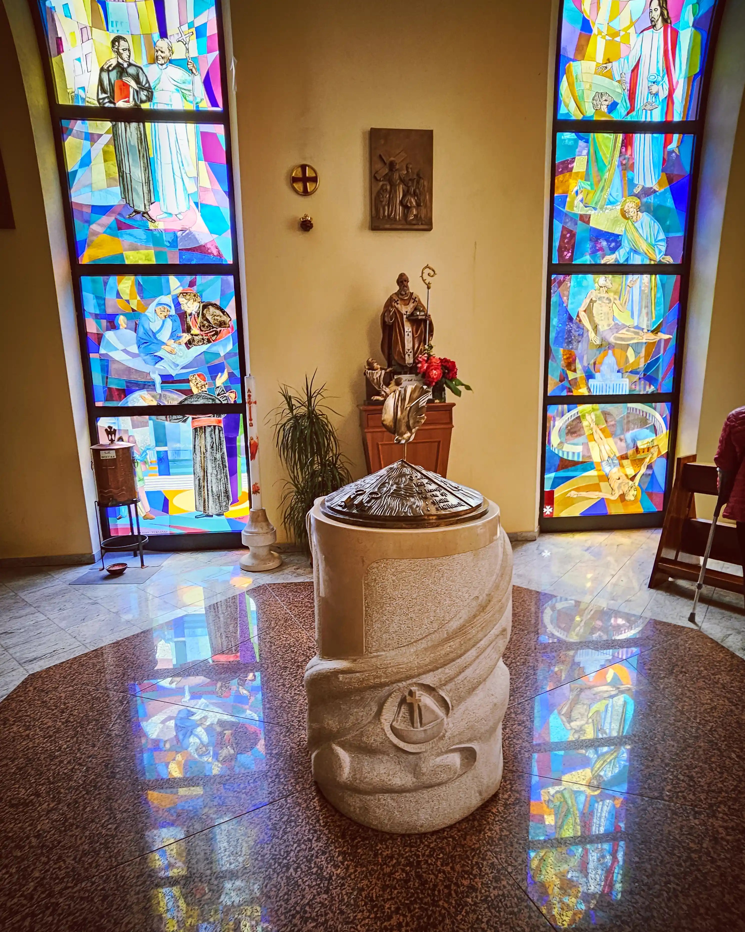 Baptismal font inside St. Paul's Cathedral surrounded by colorful stained-glass windows.