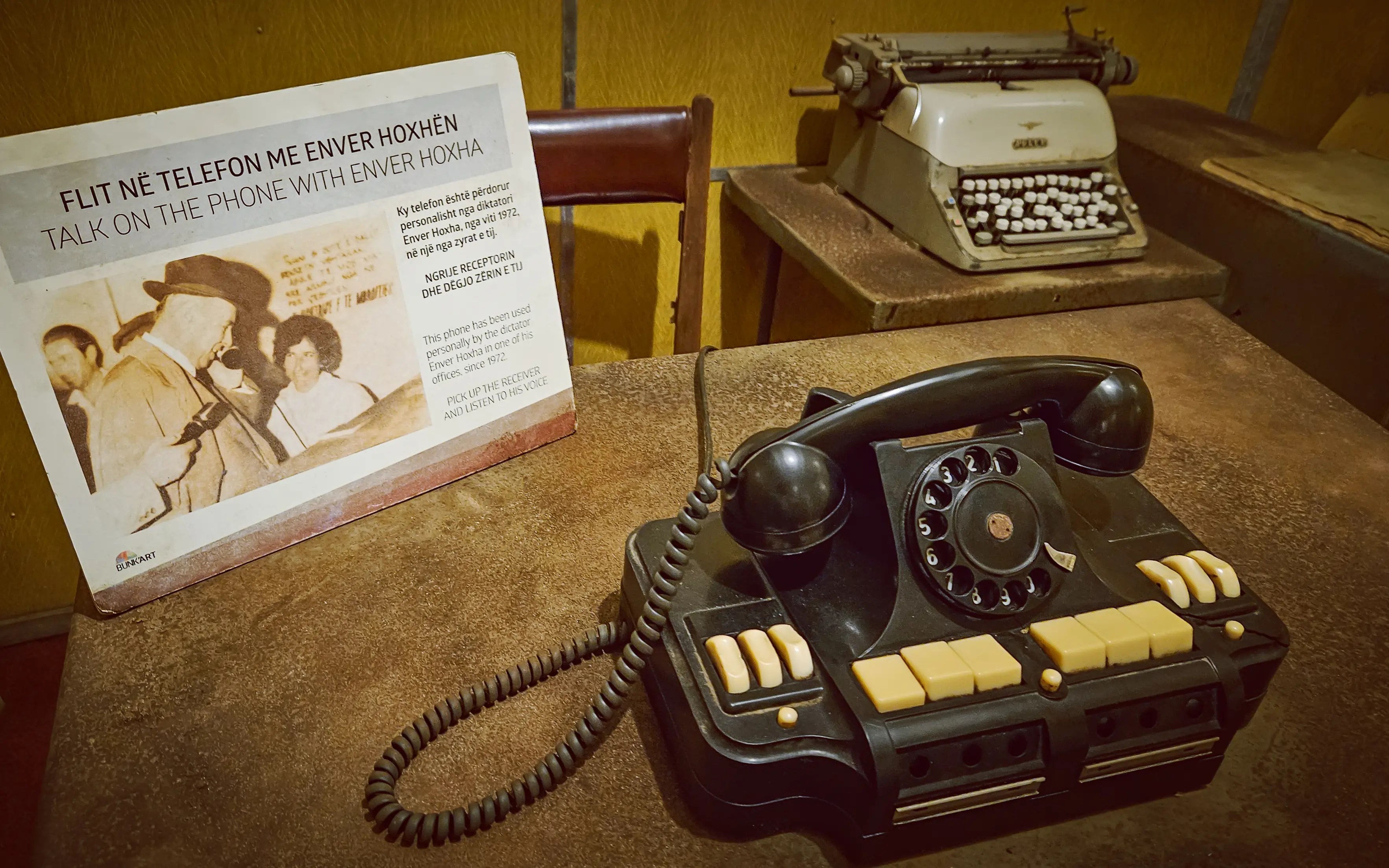 Vintage rotary telephone and typewriter displayed inside a reconstructed office at Bunk'Art 1 in Tirana.