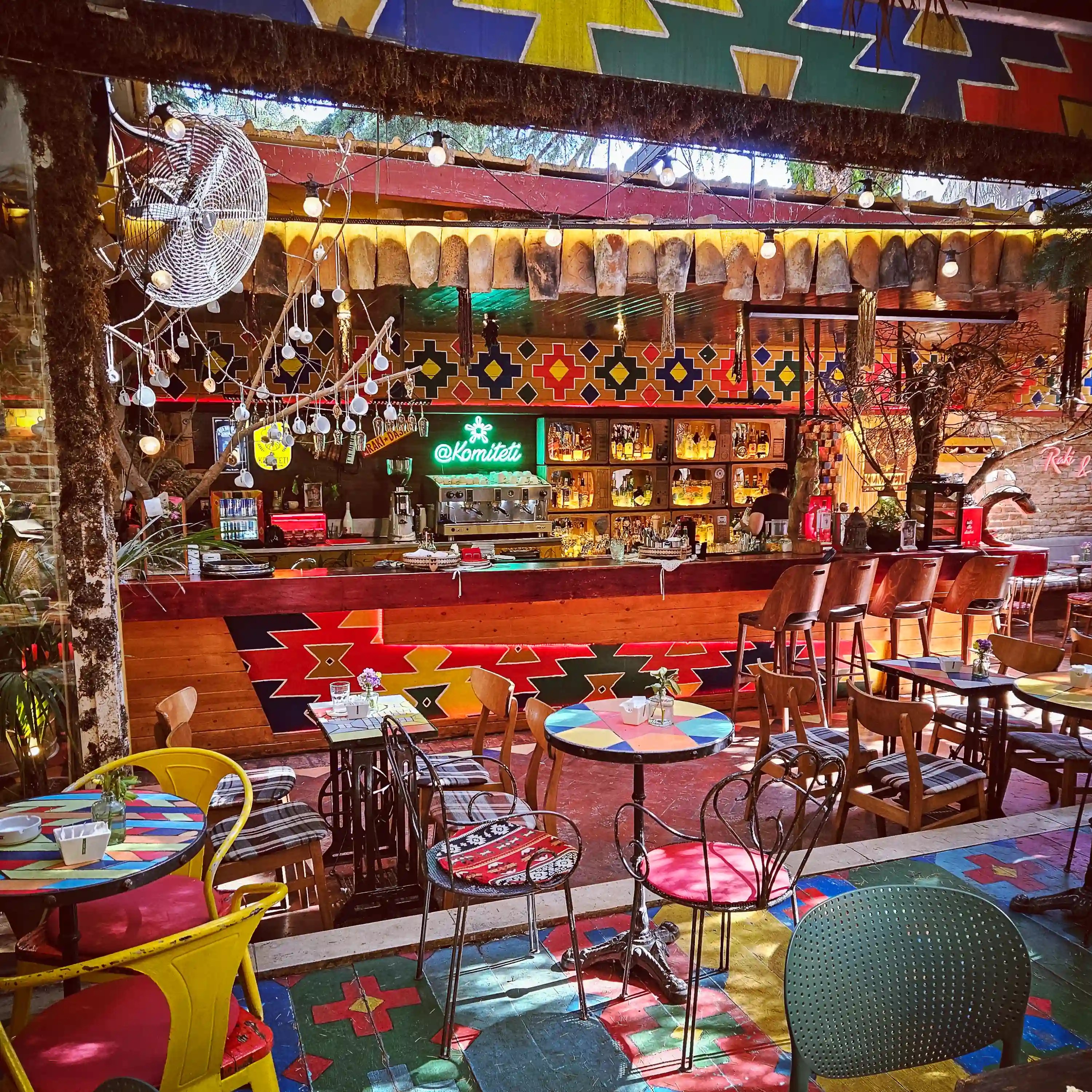 Colorful tables and chairs surround the bar area inside Komiteti – Kafe Muzeum in Tirana.