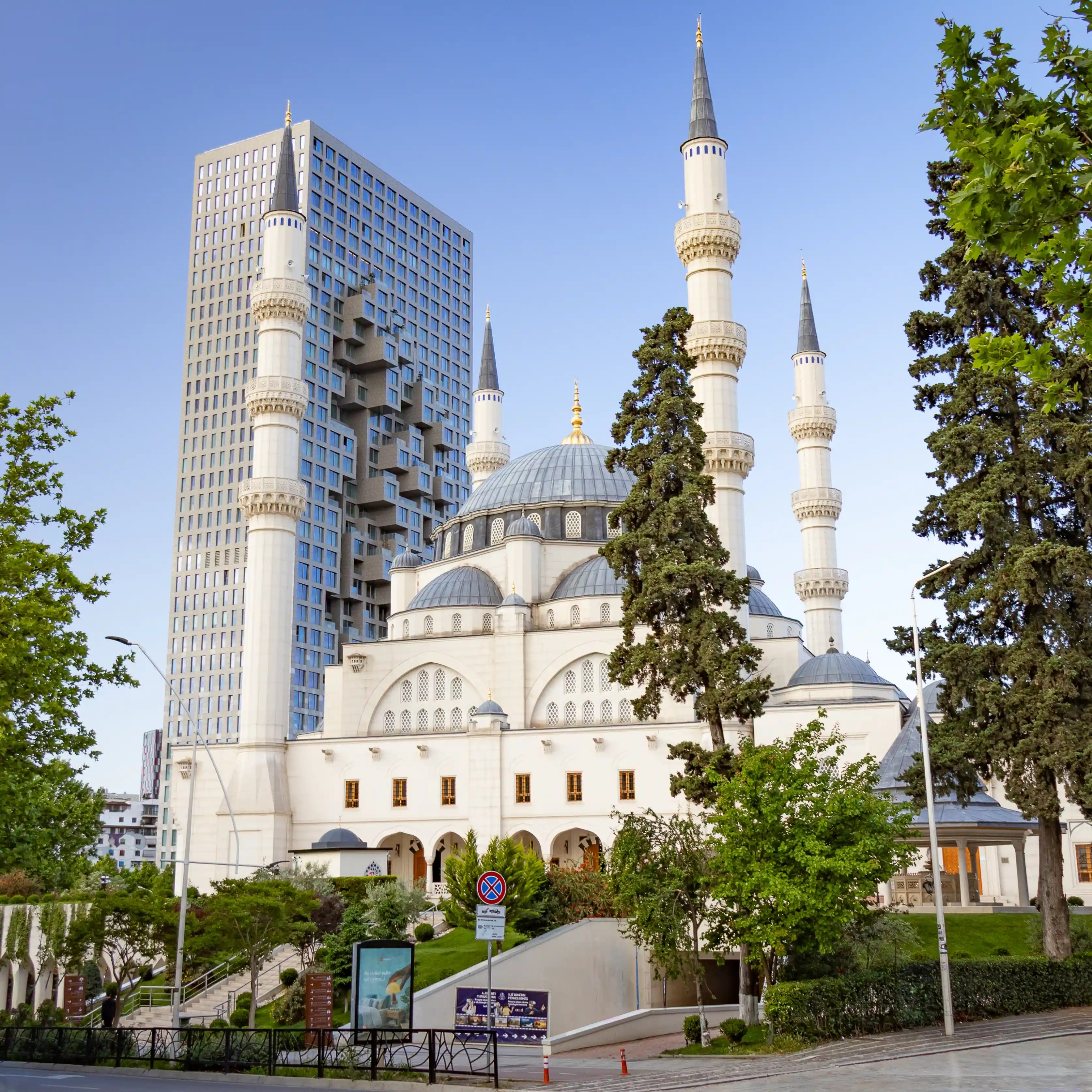 The Grand Mosque of Tirana viewed with modern high-rise buildings in the background.