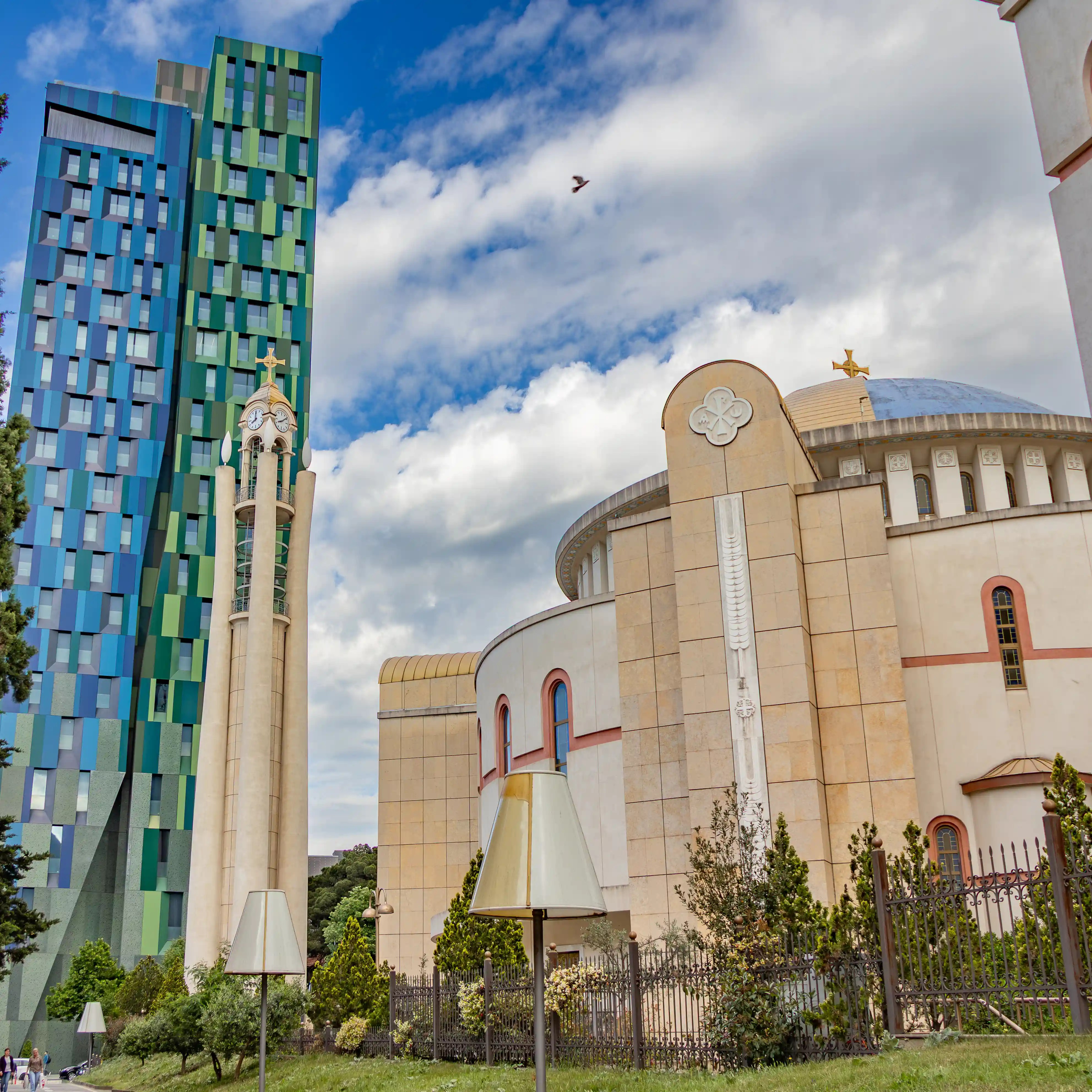 The Resurrection of Christ Orthodox Cathedral with its bell tower and colorful modern high-rise buildings nearby.