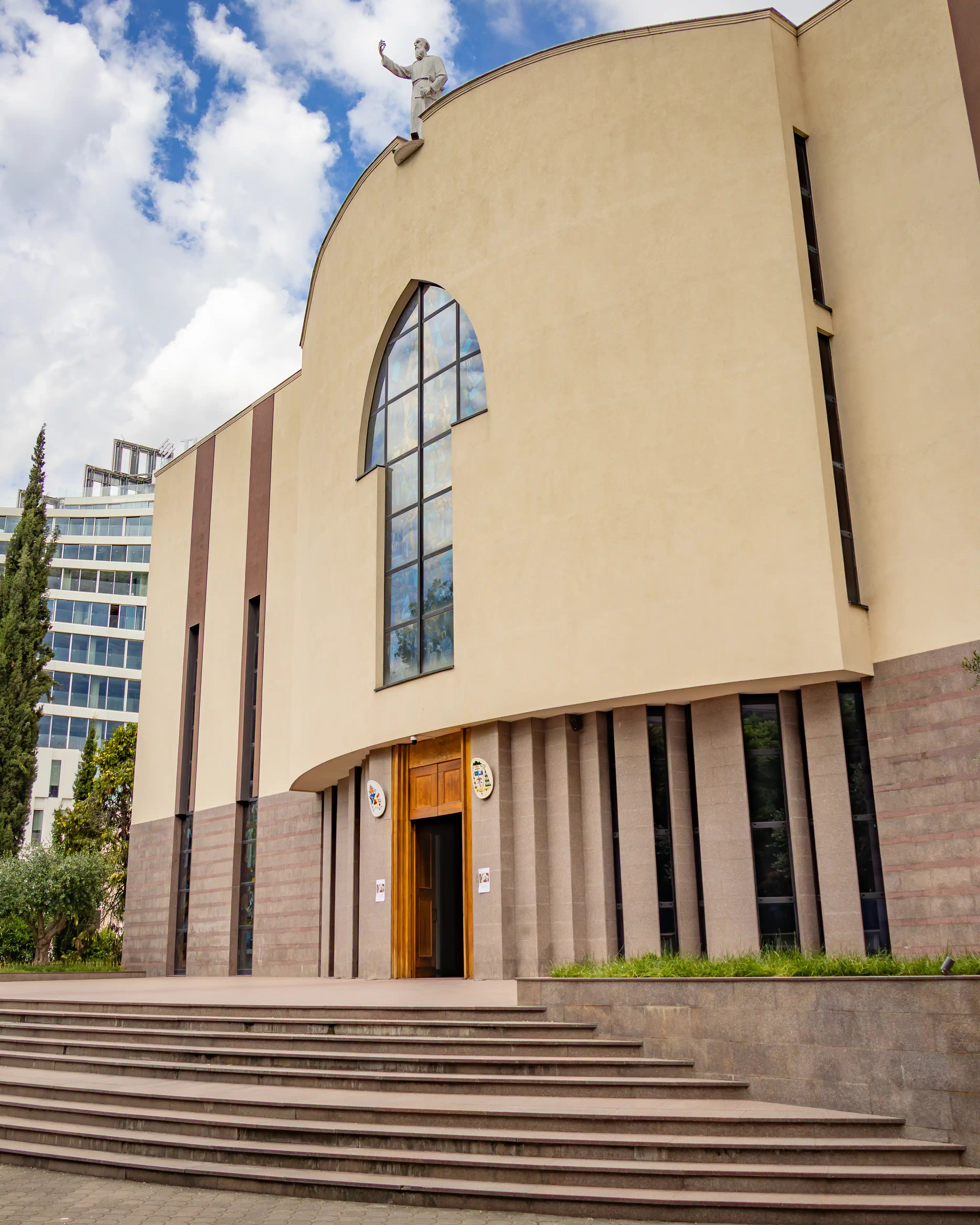 Exterior view of St. Paul's Cathedral in Tirana with its curved facade and statue on the roof.