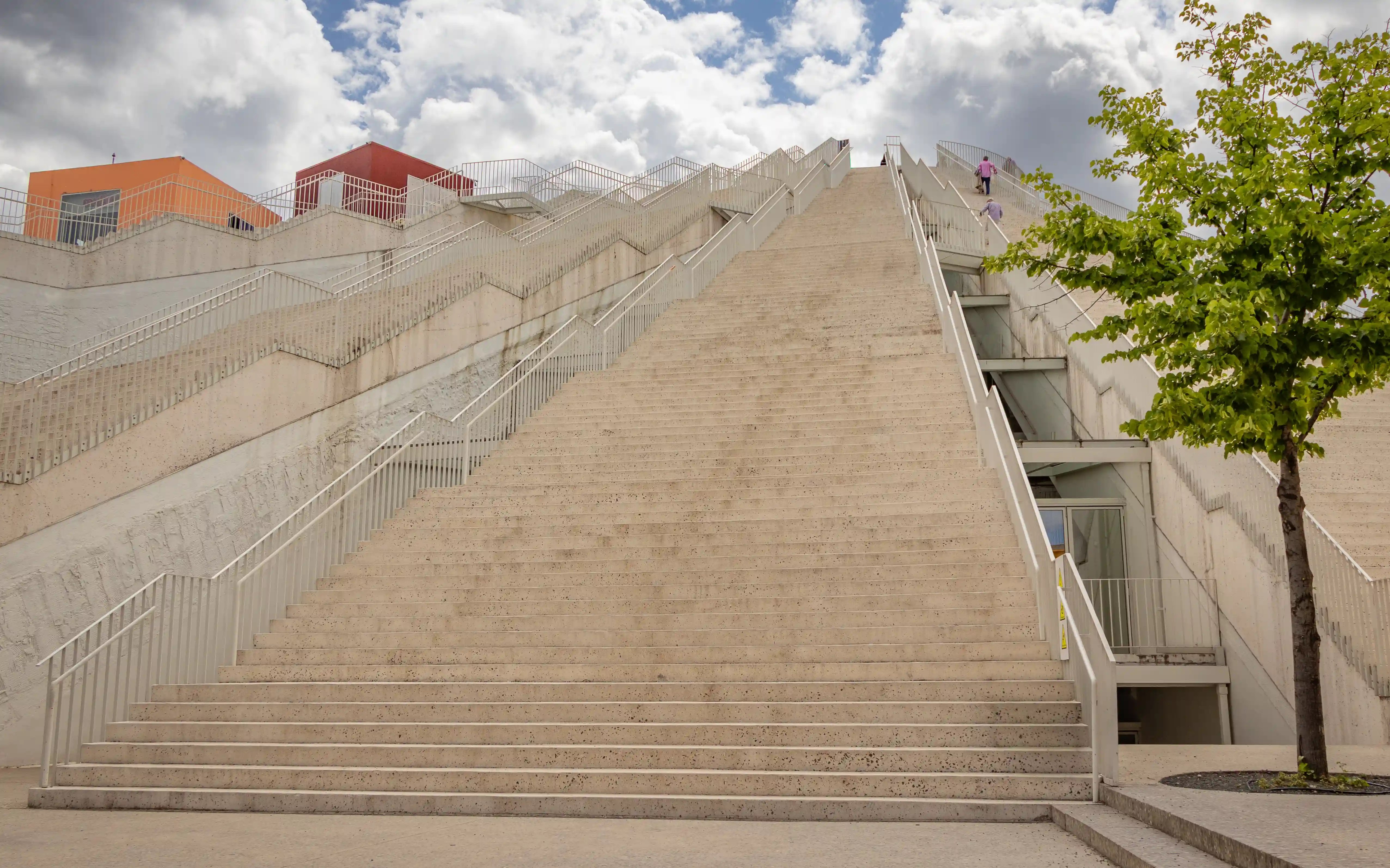 The broad staircase of the Tirana Pyramid rises toward the rooftop observation area under a cloudy sky.