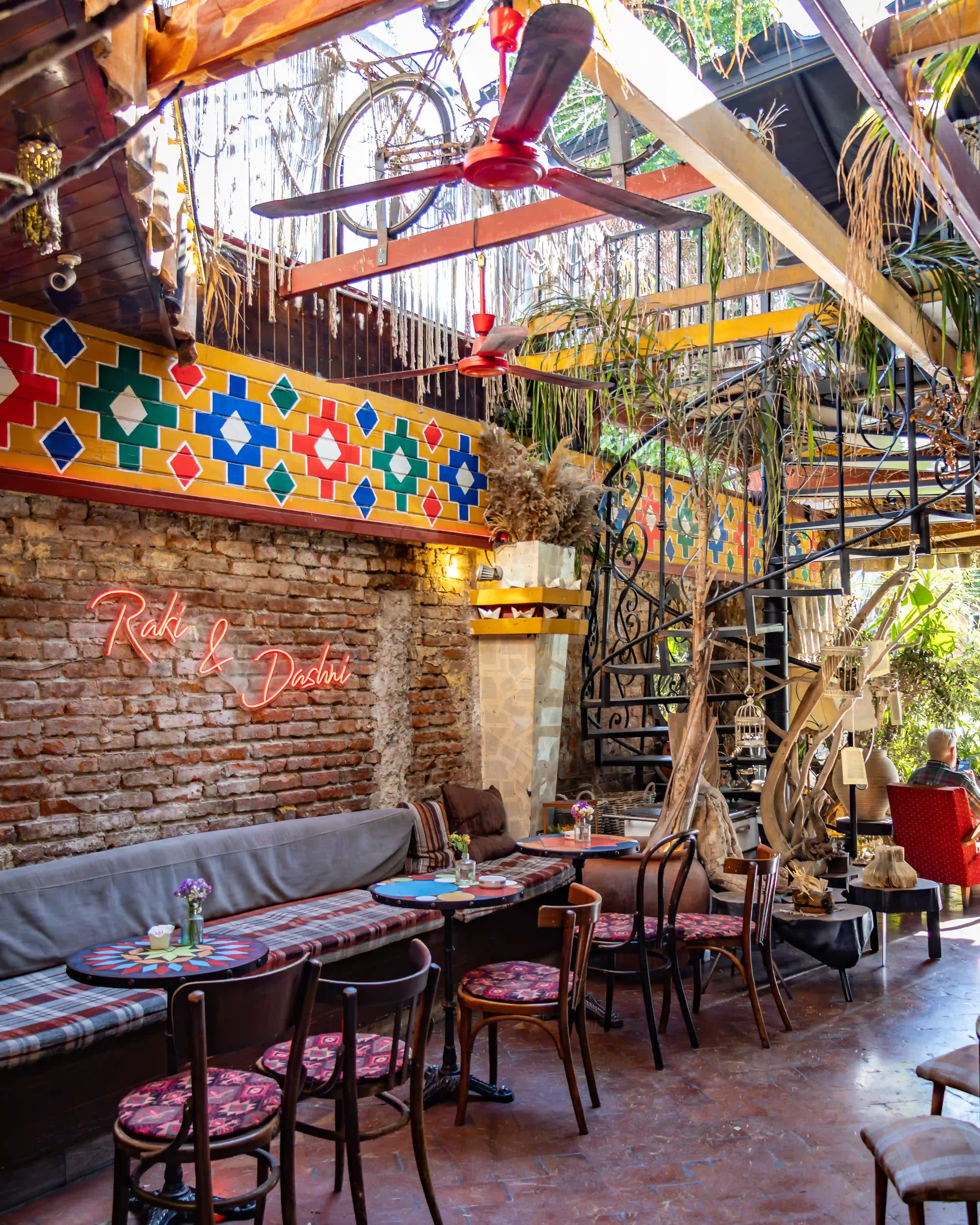 Tables, vintage furnishings, and a spiral staircase inside Komiteti – Kafe Muzeum in Tirana.