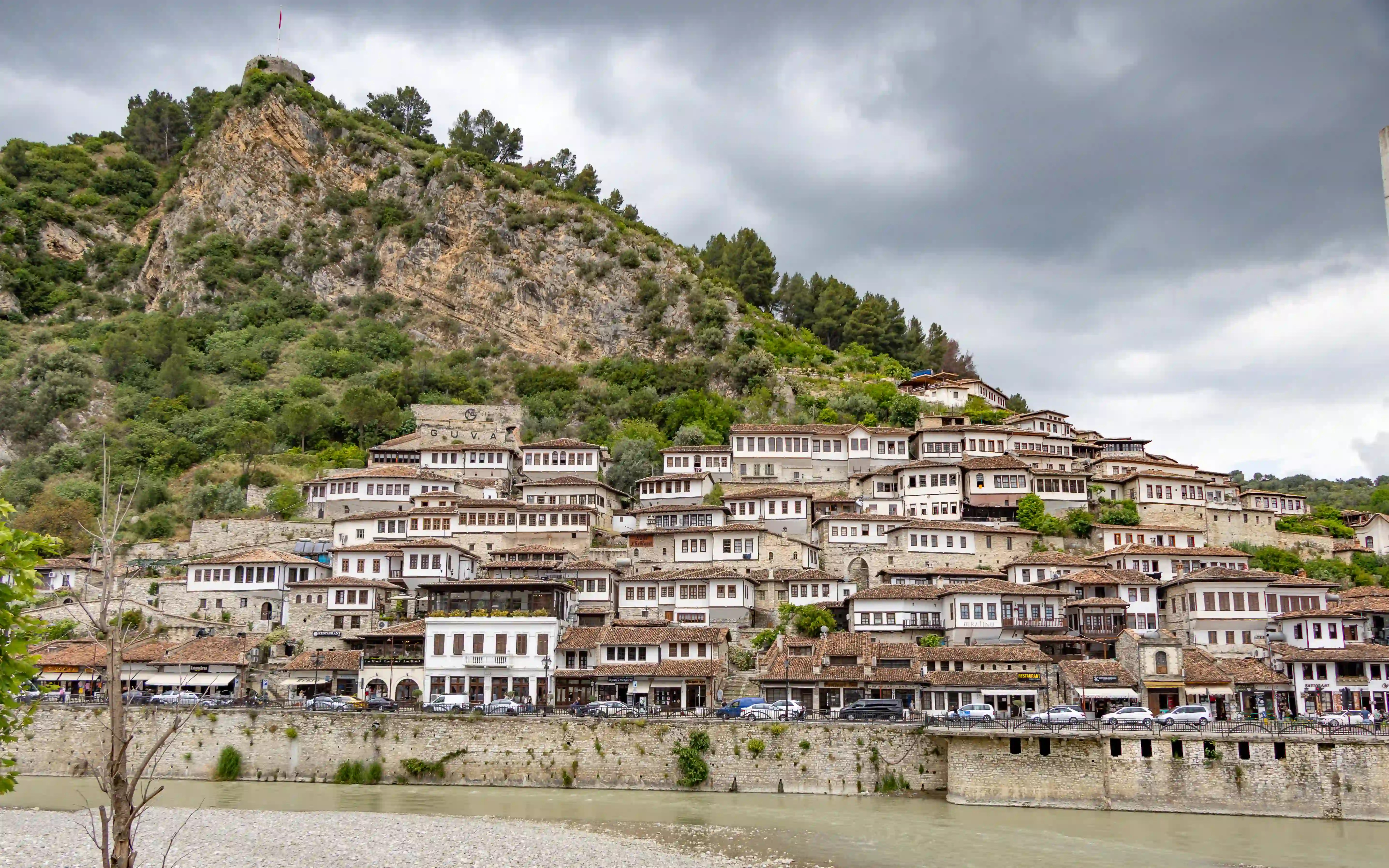 The white Ottoman houses of Berat's Mangalem Quarter climb a steep hillside above the Osum River.
