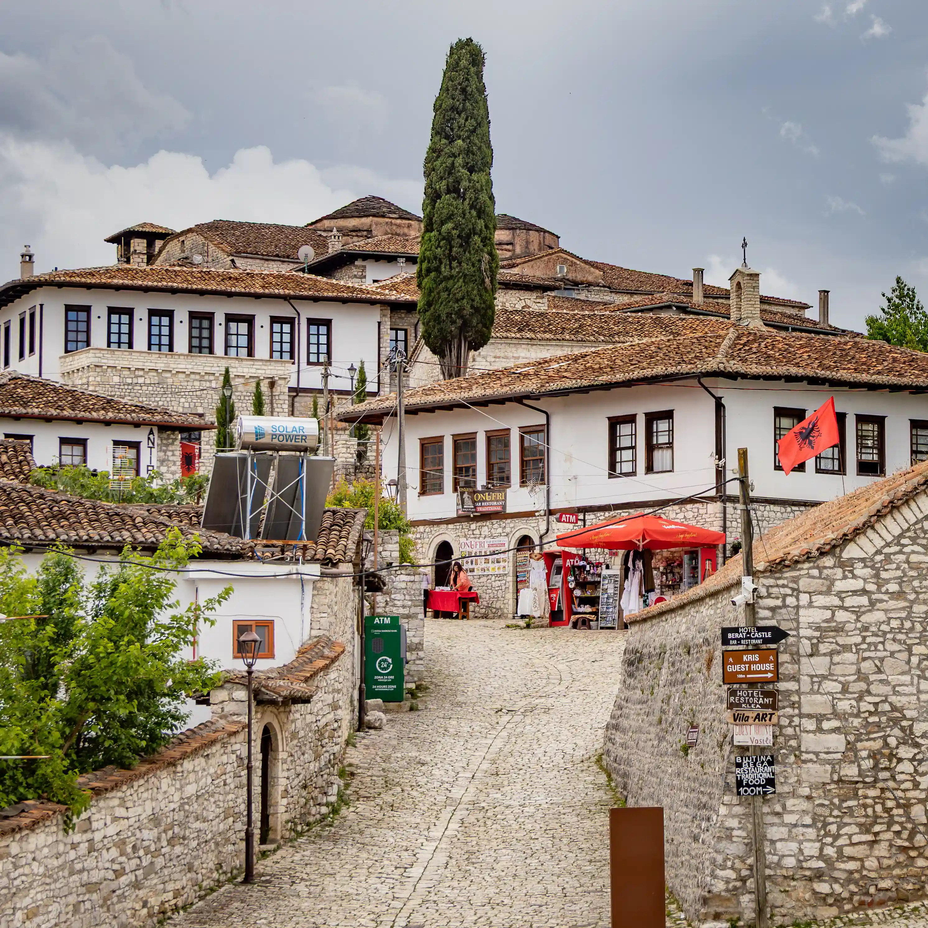 Cobblestone street lined with traditional buildings inside Berat Castle.