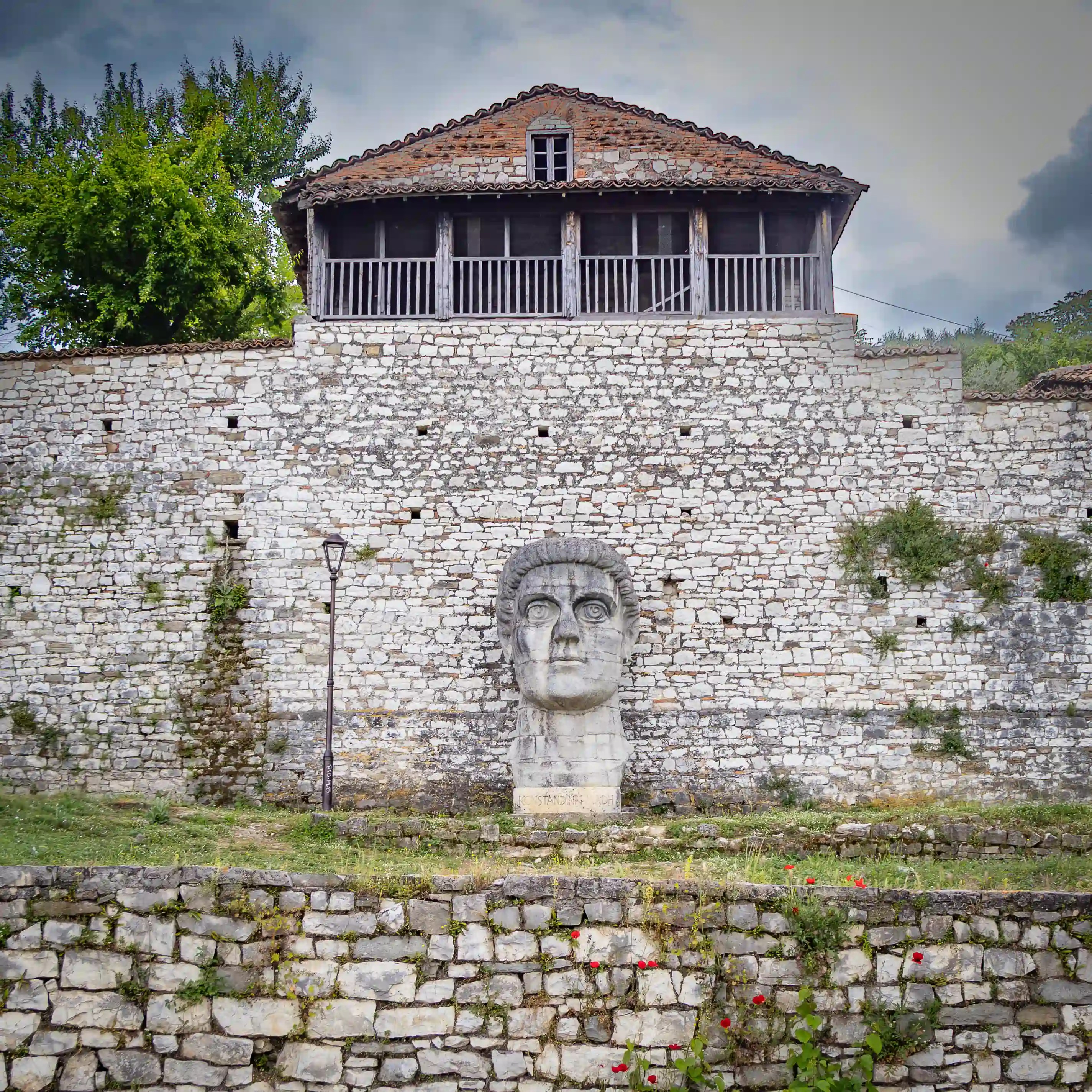 Large stone sculpture of Constantine the Great displayed against the walls of Berat Castle.