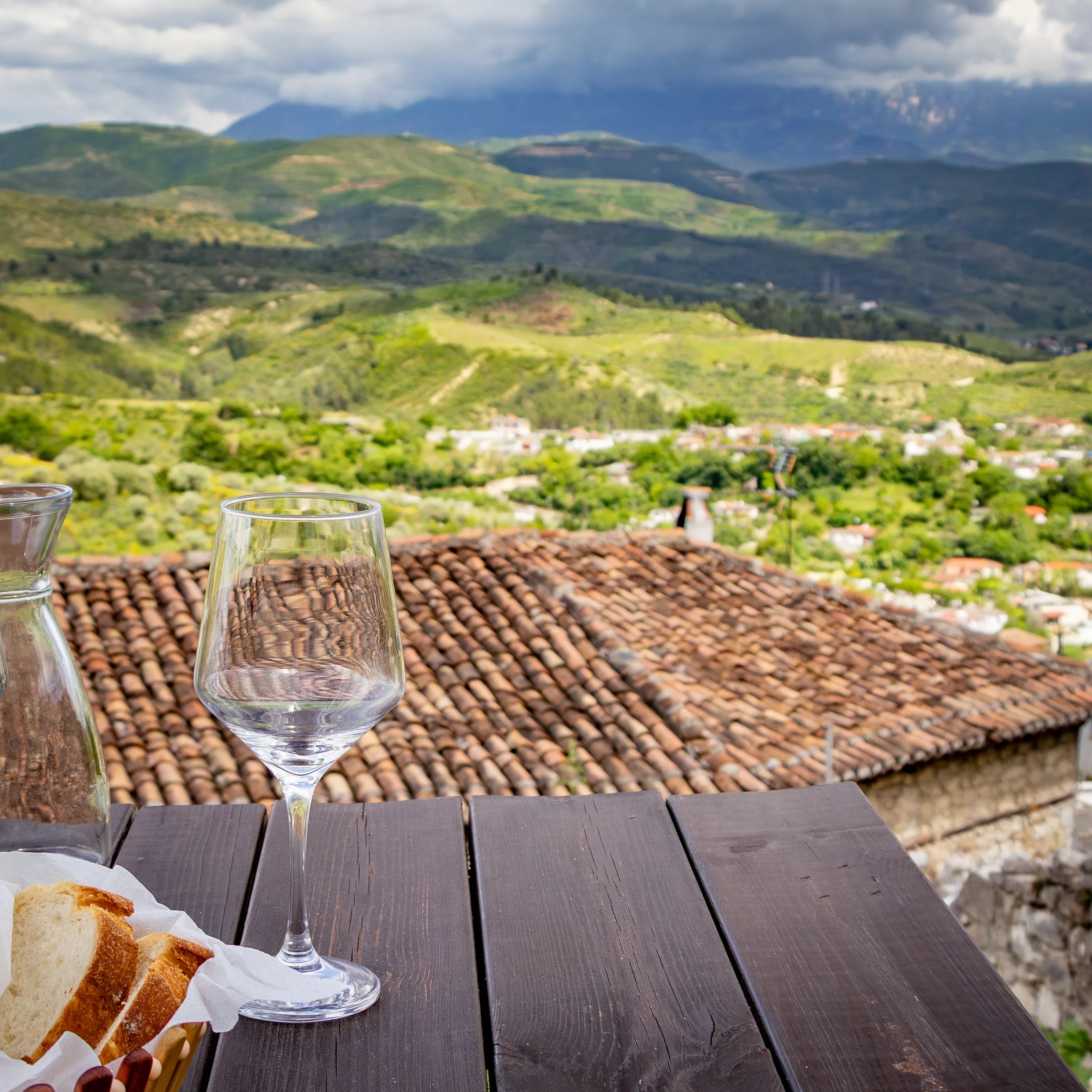 Outdoor dining table overlooking tiled rooftops and the mountains beyond Berat.