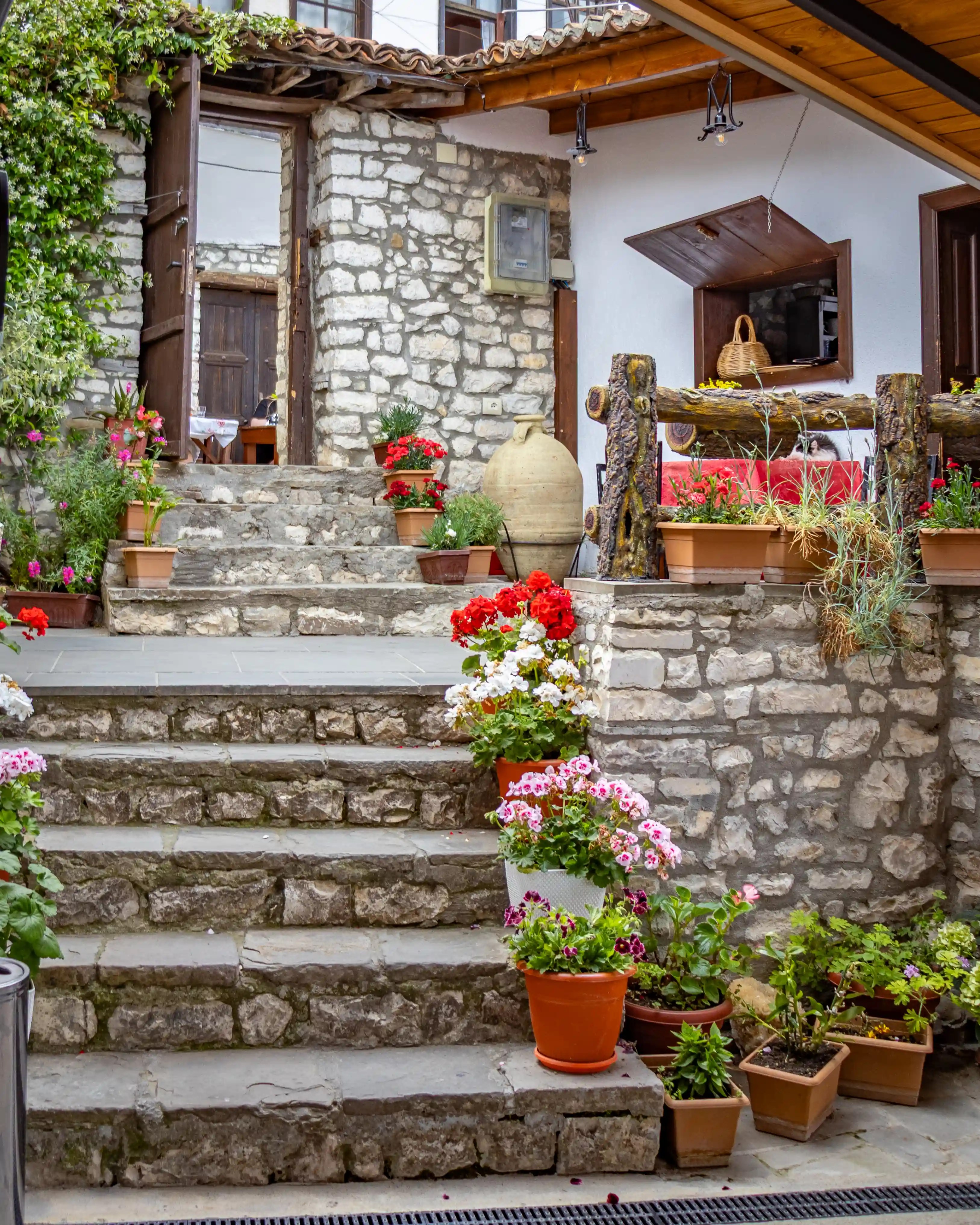 Stone terrace with colorful flower pots inside Restorant Mbrica in Berat Castle.