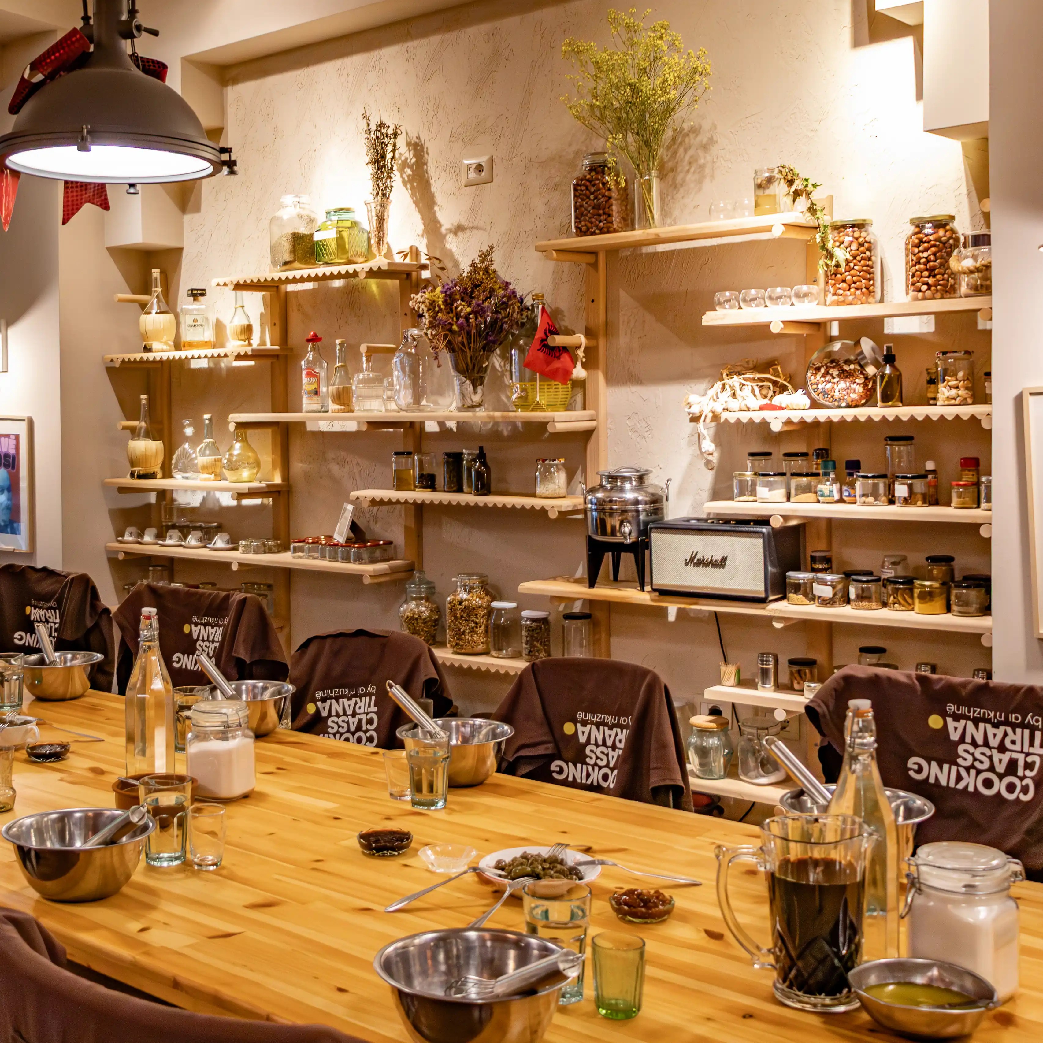Shelves filled with jars, herbs, and cooking ingredients inside a cooking studio in Tirana.
