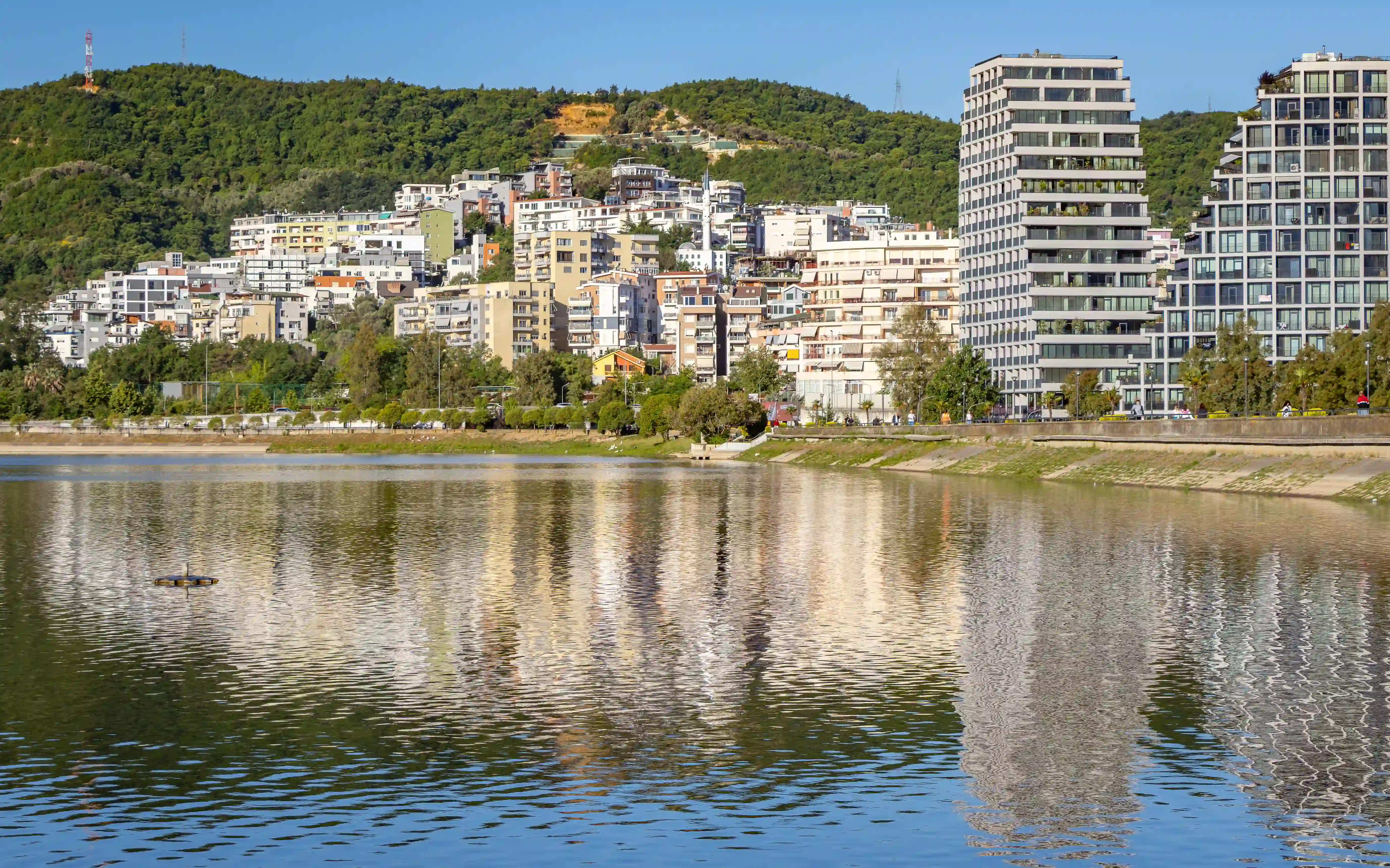 Modern apartment buildings reflected in the waters of Tirana's Artificial Lake.