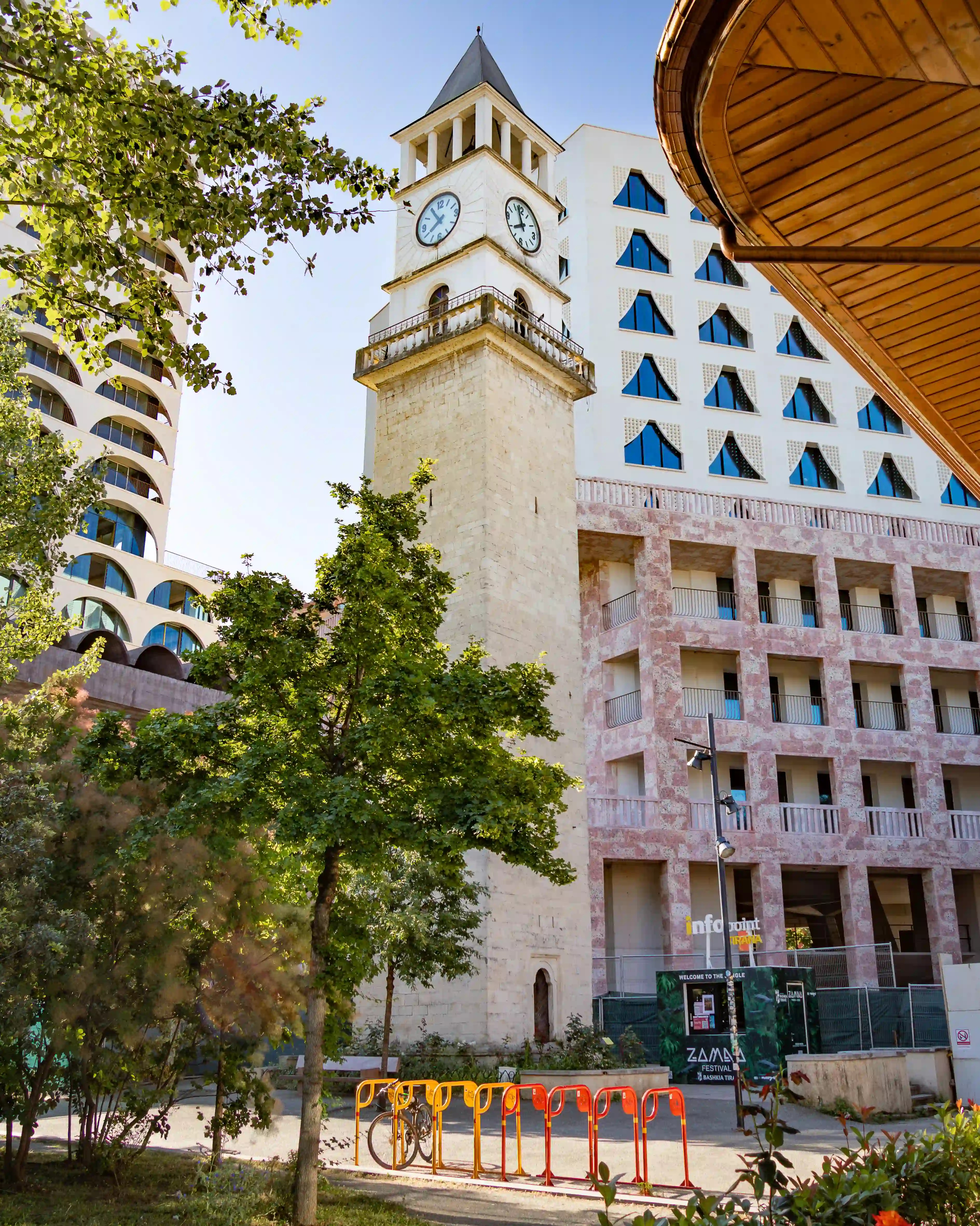 The Clock Tower of Tirana rises above trees and modern buildings in the city center.